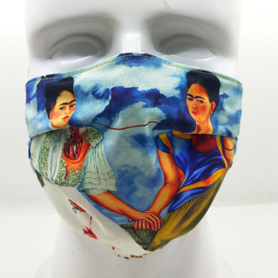 A face mask with a print from Frida Kahlo's Two Fridas painting, featuring two versions of the artist connected by a vein.